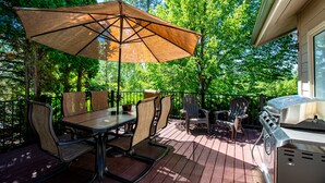 A deck with a table, chairs, a grill, and a large umbrella. - Town Home with Hot Tub, Sleeps 6 in Meadow Lake Resort and Golf Course (Columbia Falls)