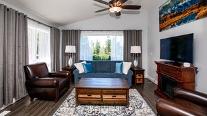 A living room with a sofa, armchairs, a coffee table, a fireplace, a TV, and a ceiling fan. - Town Home with Hot Tub, Sleeps 6 in Meadow Lake Resort and Golf Course (Columbia Falls)