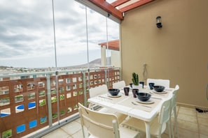 Un balcone con un tavolo apparecchiato per mangiare, un cactus e una vista su un paesaggio lontano.