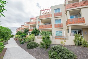 A multi-story hotel with balconies, a paved walkway, and various plants. - Holiday Apartment Luxury Junto Al Mar close to the Beach with Terrace (EL MEDANO)
