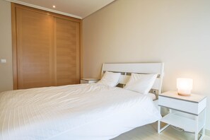 A bedroom with a bed, nightstands, a bedside lamp, and a wooden wardrobe. - Holiday Apartment Luxury Junto Al Mar close to the Beach with Terrace (EL MEDANO)