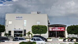 Un edificio con un letrero que dice 'ELLO RESTAURANTE' y coches estacionados adelante.