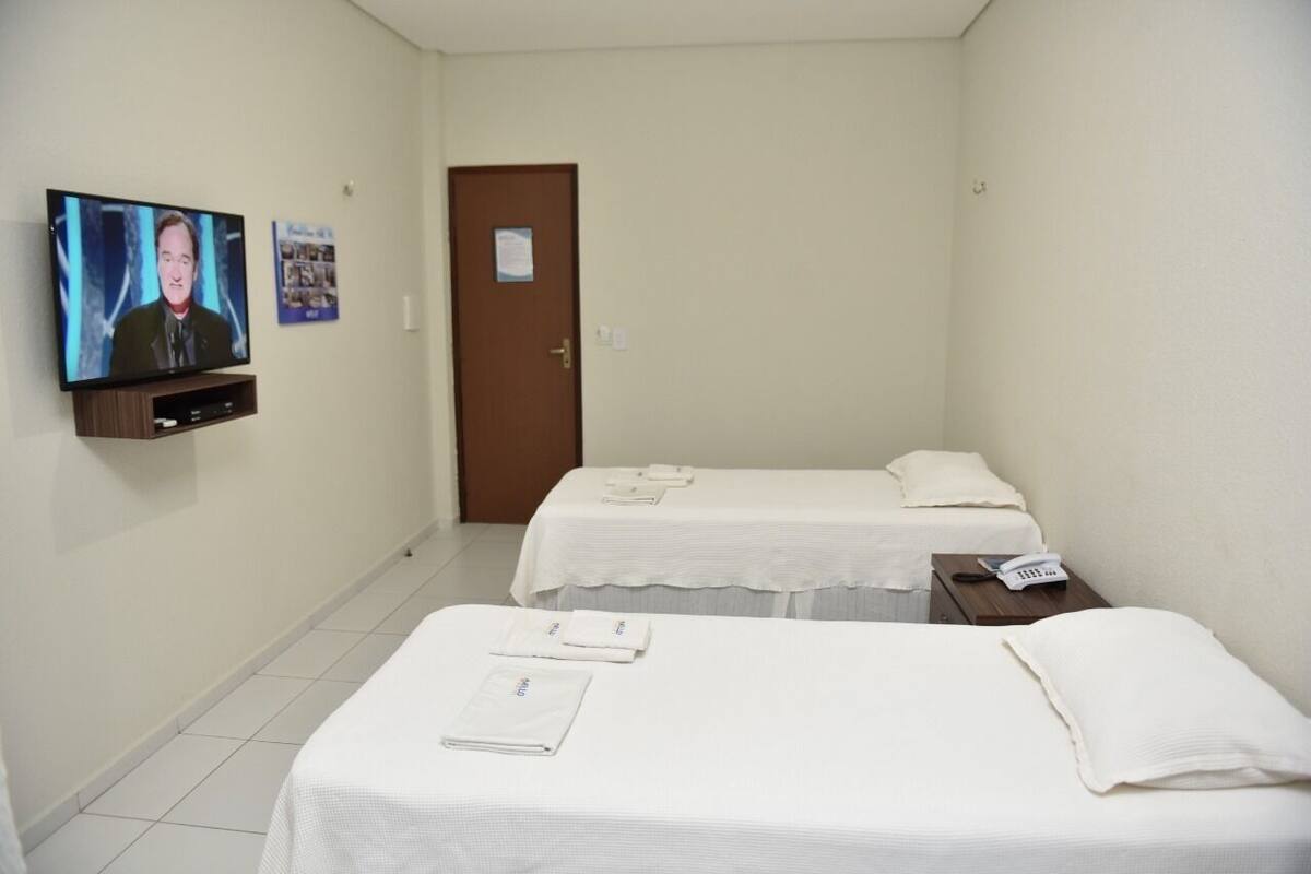 Una habitación de hotel con dos camas, un televisor en la pared y una puerta.