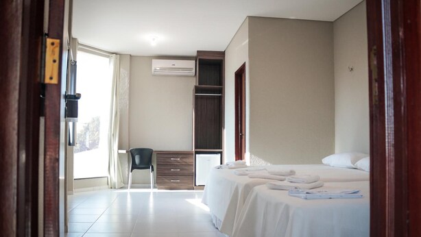 Una habitación de hotel con cama, escritorio, silla y armario.