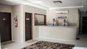 Zona de recepción de un hotel con recepcionista, un extintor y un letrero que dice 