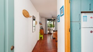 Un corridoio con una porta bianca, un frigorifero blu e un'area pranzo con tavolo e sedie.