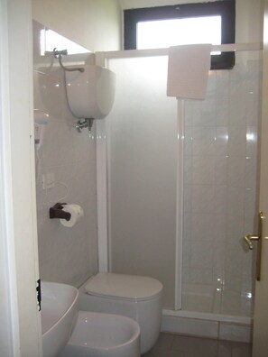 A bathroom with a toilet, a bidet, and a shower enclosure.