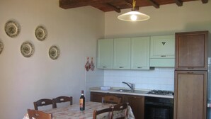 Una cocina con una mesa de comedor, sillas, un lavamanos, armarios y una estufa.