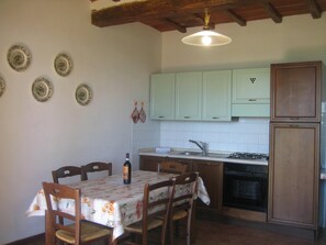 Una cocina con una mesa de comedor, sillas, un lavamanos, armarios y una estufa.