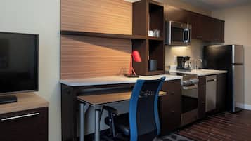 Cocina compacta equipada con microondas, cafetera y refrigerador.