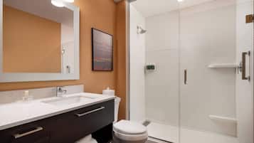 Un baño moderno con un espejo grande, dos lavamanos, un inodoro y una ducha con mampara de vidrio.