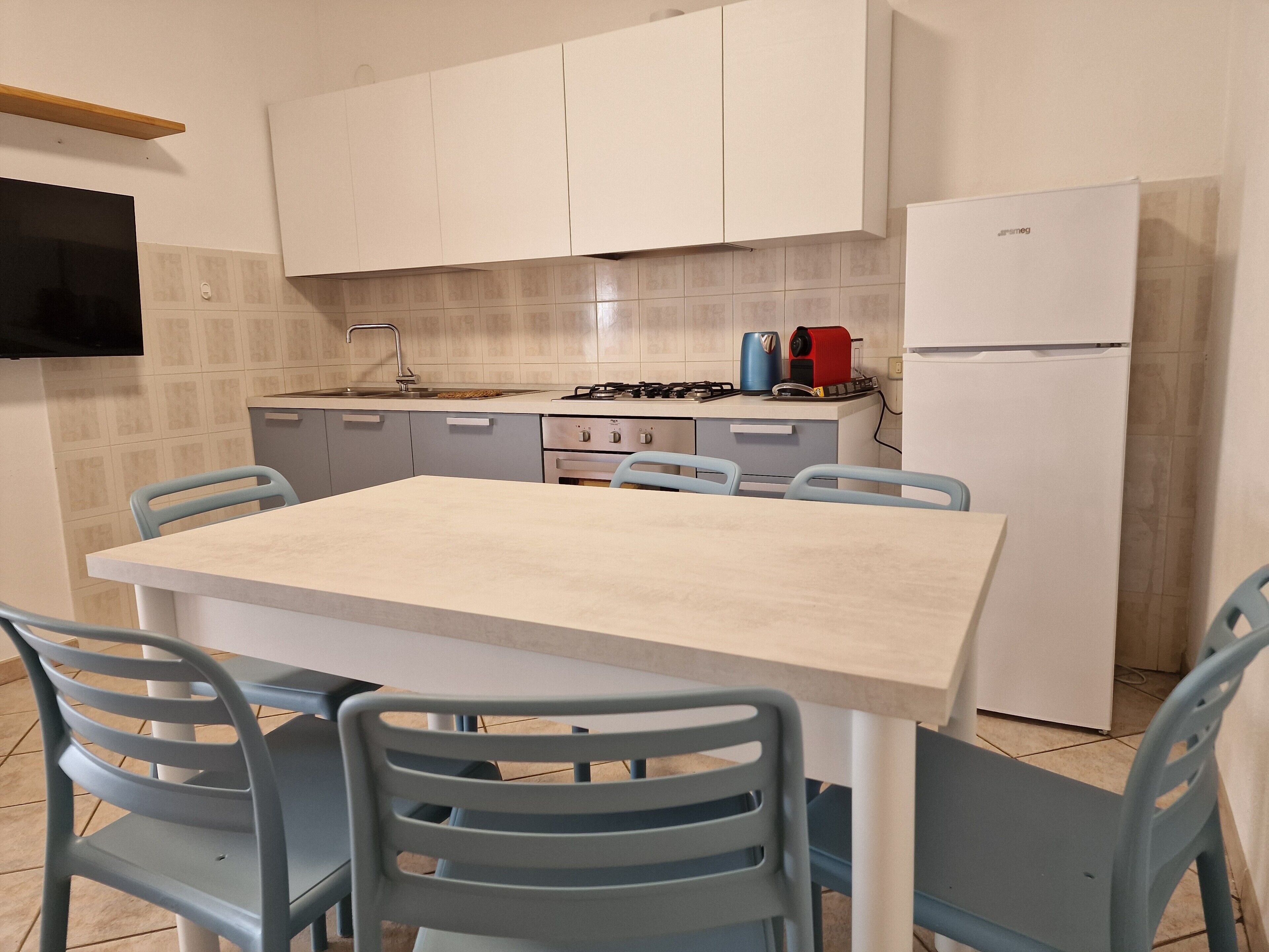 Une cuisine équipée d’une table et de chaises, d’une cuisinière, d’un évier et d’un réfrigérateur.