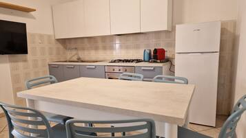 Une cuisine équipée d’une table et de chaises, d’une cuisinière, d’un évier et d’un réfrigérateur.