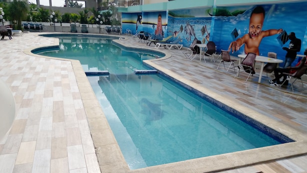 An indoor swimming pool with tiled flooring and lounge chairs. - Complexe Hôtelier Asthoria palace (Abidjan)