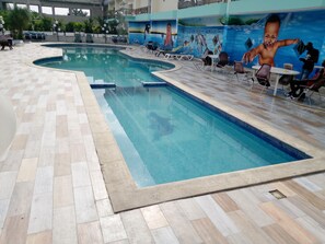 An indoor swimming pool with tiled flooring and lounge chairs.