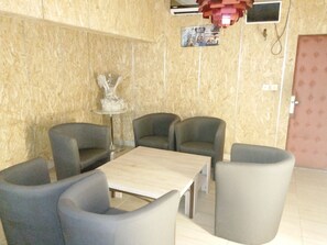 Una habitación con pared de madera, una estatua, una mesa y cuatro sillas.