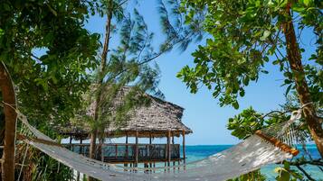 Na praia, areia branca, espreguiçadeiras, guarda-sóis