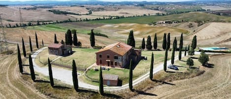 Una propiedad rural con una casa grande rodeada por una cerca, un granero pequeño y una piscina.