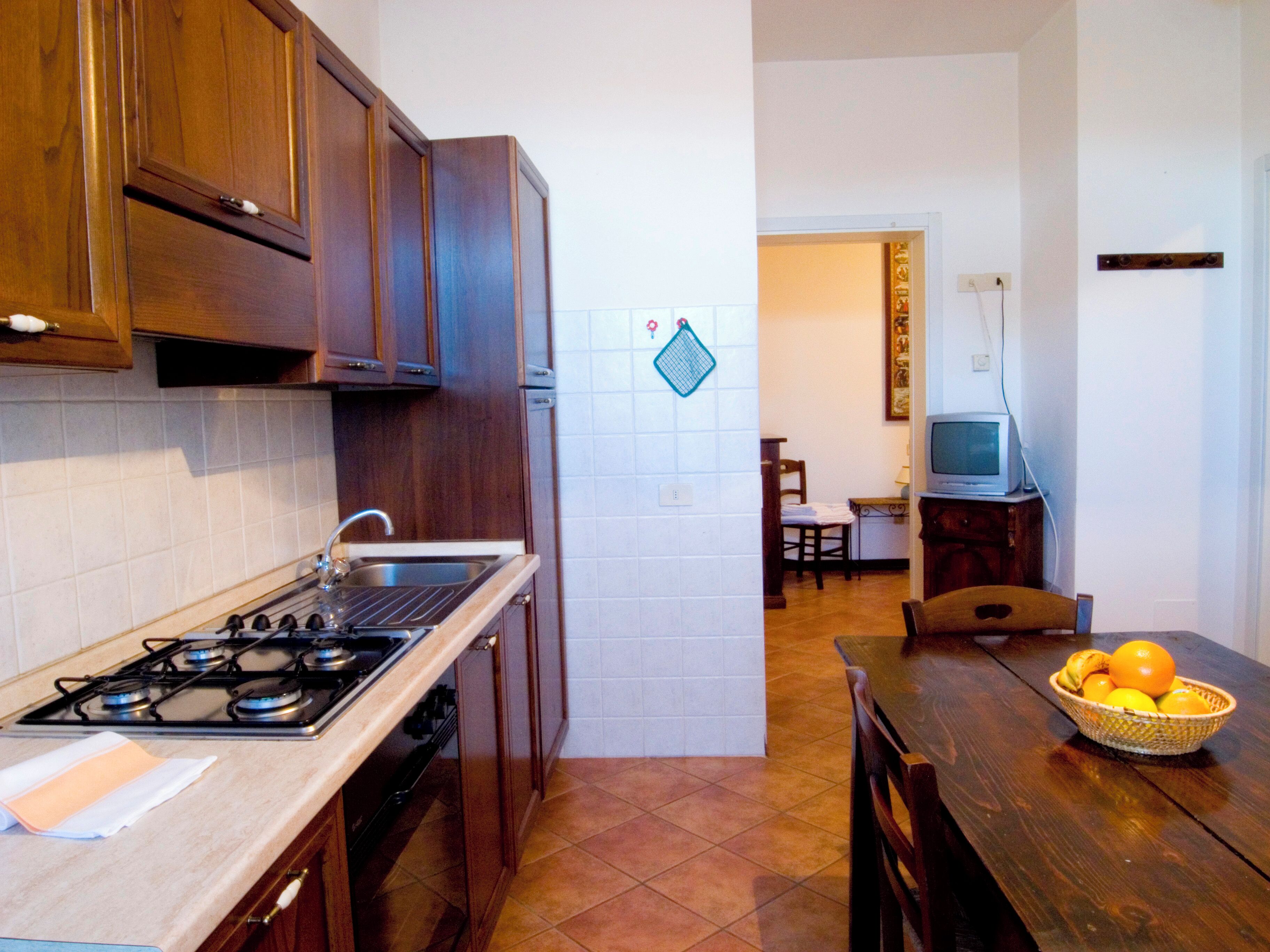 A kitchen with wooden cabinets, a stove, and a dining area with a table and chairs.