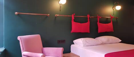 A room with a bed, a chair, and two wall-mounted light fixtures.