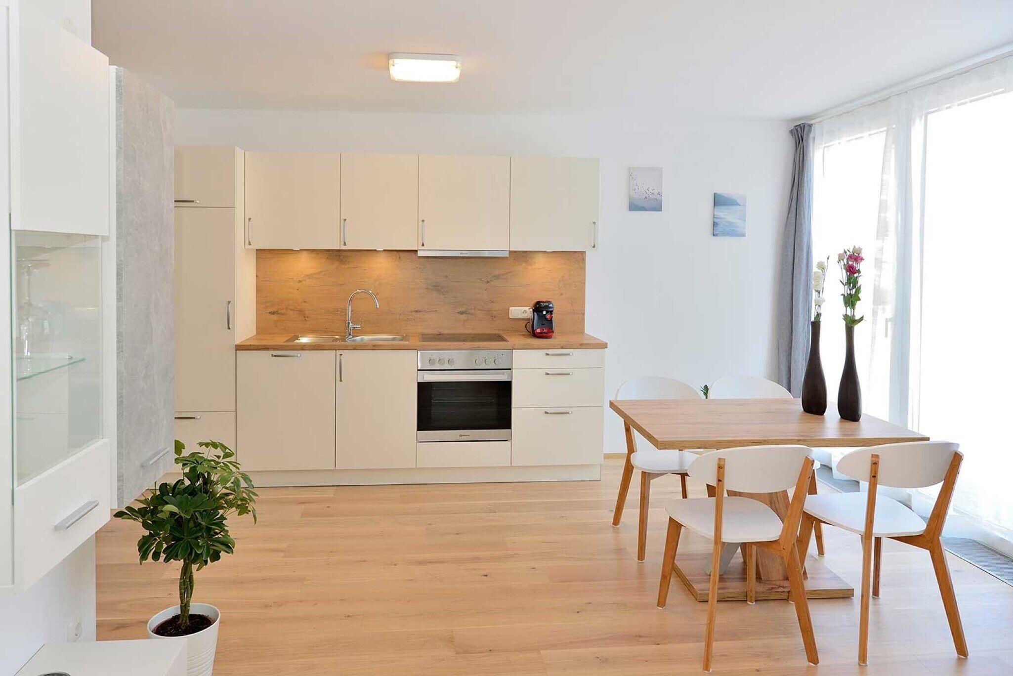 Una cocina moderna con armarios blancos, encimera de madera y comedor con mesa y sillas.