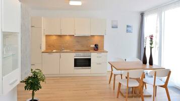 Une cuisine moderne avec des meubles blancs, un plan de travail en bois et un coin repas comprenant une table et des chaises.