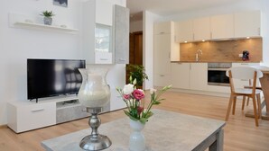A modern living room with a flat-screen TV, a decorative vase, and a dining area with a table and chairs.
