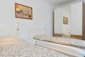 Un dormitorio con dos camas, un espejo grande y un cuadro en la pared.