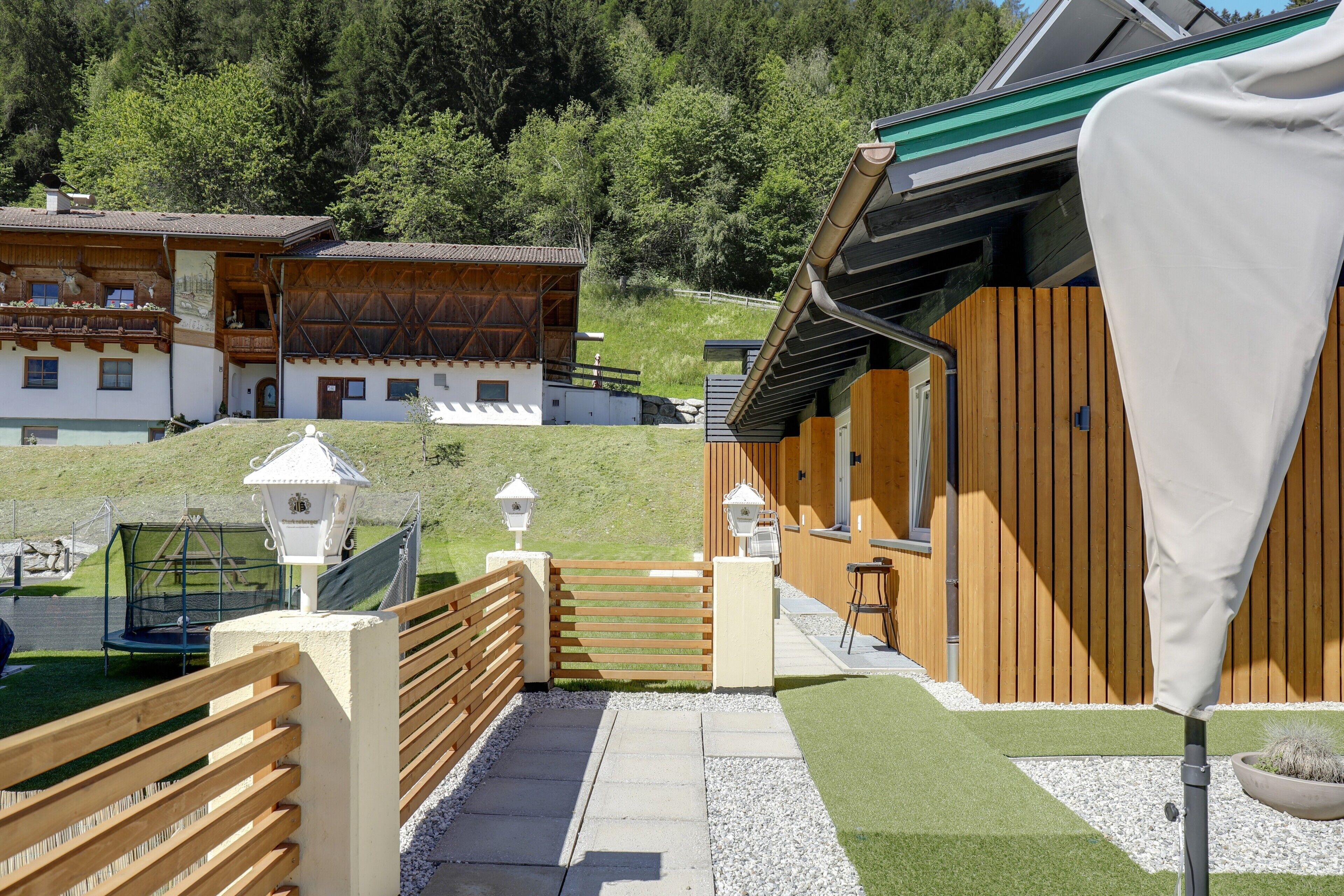 Un bâtiment en bois doté d’un balcon, d’une clôture en bois et d’un chemin pavé menant à un portail.