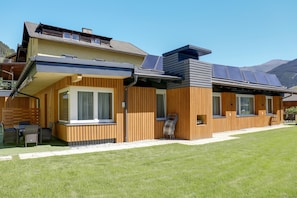 Une maison moderne à deux étages, avec une façade en bois, de grandes fenêtres et un ensemble de panneaux solaires.