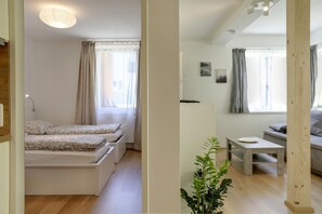 Une chambre moderne avec un lit, une petite table, une plante et un canapé.