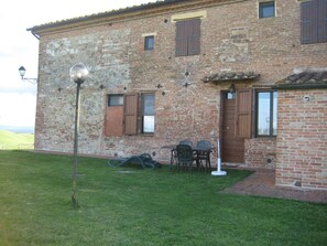 Un edificio de ladrillo rústico con un pequeño patio amoblado con mesa y sillas.