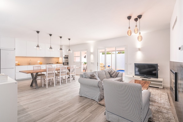 A modern living room with a sofa, TV, and dining area.
