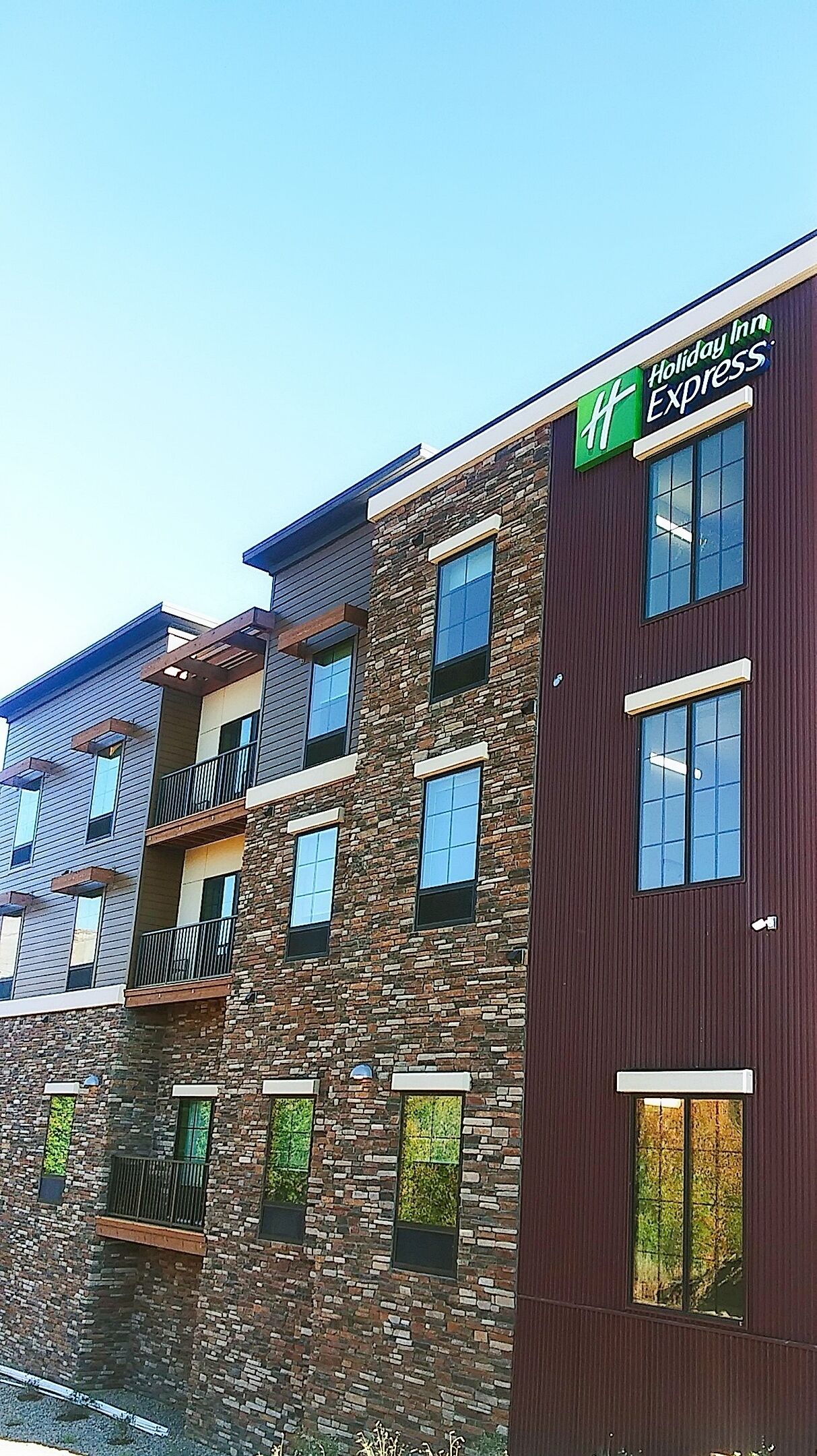 A multi-story building with a Holiday Inn Express sign, featuring a stone facade and multiple balconies.