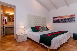 Une chambre à coucher avec un grand lit, une table de chevet, un miroir, un tableau et un mur en pierre.