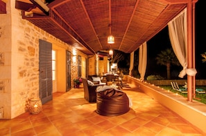 An outdoor patio with stone walls, a covered seating area, and a dining setup.