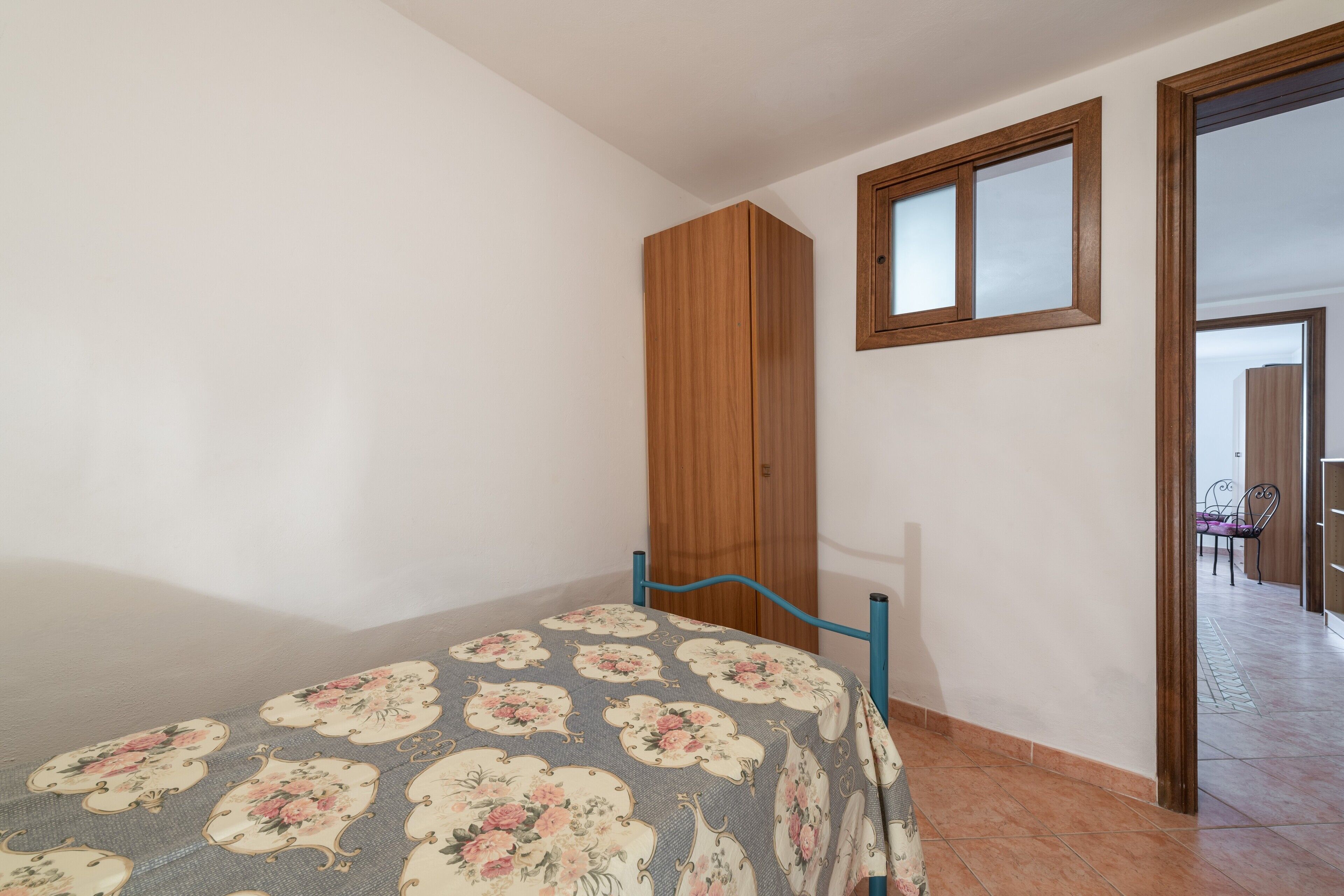 Un dormitorio con cama, armario y ventana.