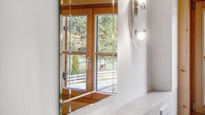 Un baño moderno con un espejo grande, techo de madera y vistas a una terraza de madera.