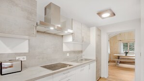Cocina moderna con tostadora integrada, pileta de acero inoxidable y zona de comedor de madera con banco.