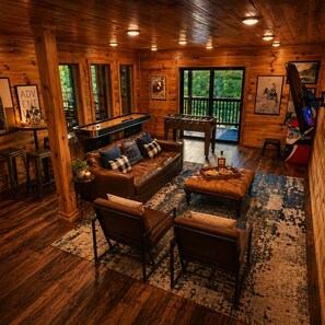 Un interior acogedor de cabaña de madera con un sofá, sillas y una mesa de fútbol de mesa.