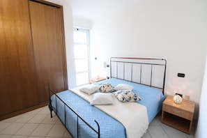Une chambre à coucher comprenant un lit, une armoire en bois, une table de chevet et une petite table de nuit.
