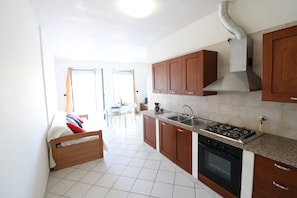A kitchen with wooden cabinets, a gas stove, a sink, and a ventilation hood.