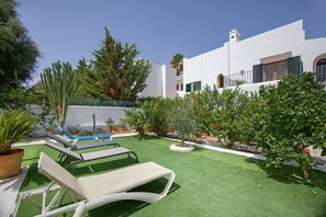 A white building with a balcony, a pool, and artificial grass.
