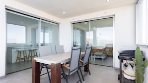 A modern dining area with a glass partition, a wooden table, and chairs.