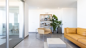 A modern living room with a sofa, a chair, a coffee table, and a bookshelf.