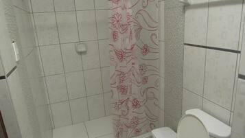 Une salle de bain avec douche, toilettes et murs carrelés.