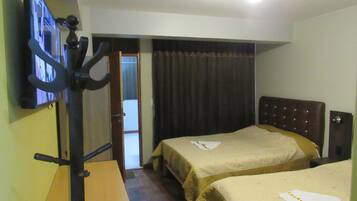 A hotel room with two beds, a desk, a television, and a door leading to a balcony.