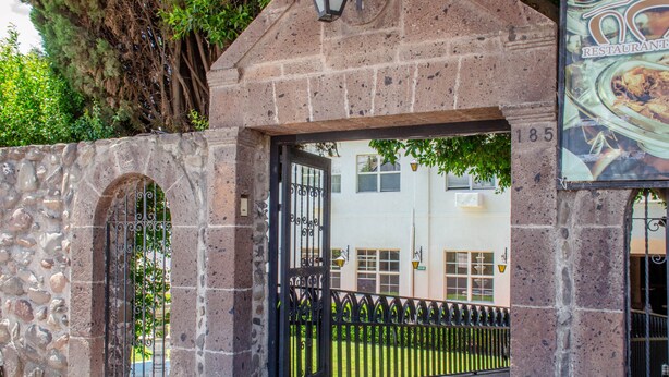 A stone archway with a metal gate leading to a building with the number 185.
