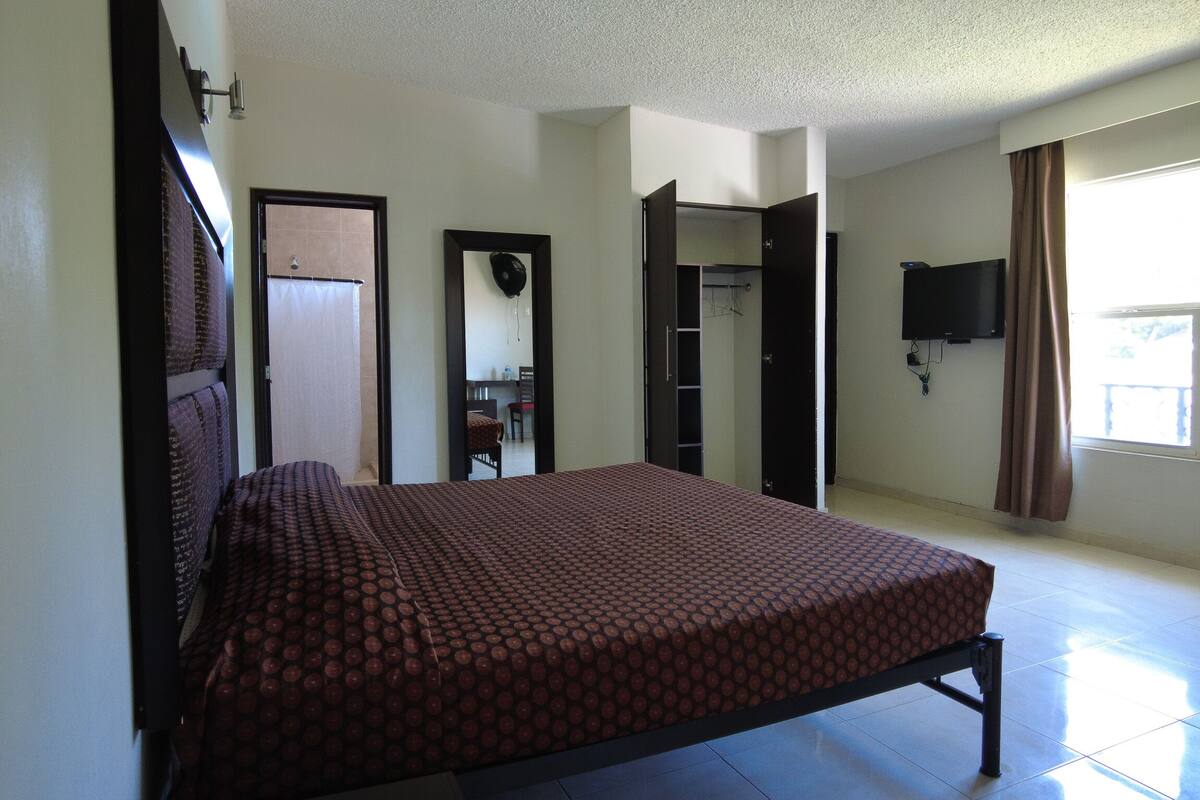 Ein Hotelzimmer mit Bett, Fernseher und einem durchgegangenen Tür sichtbaren Badezimmer.