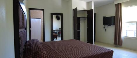 A hotel room with a bed, a television, and a bathroom visible through an open door.